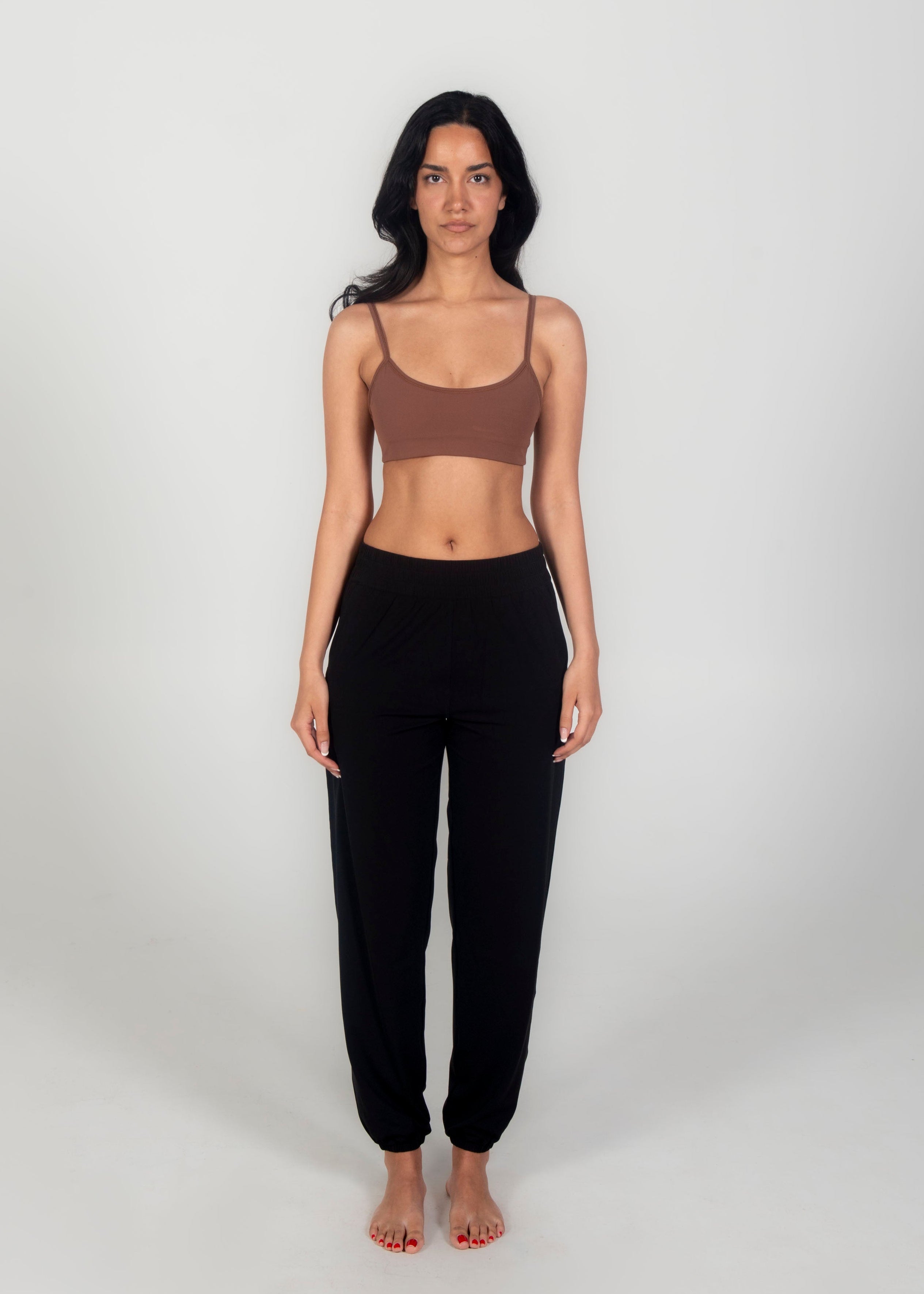Woman wearing a brown crop top and black pants on a white background