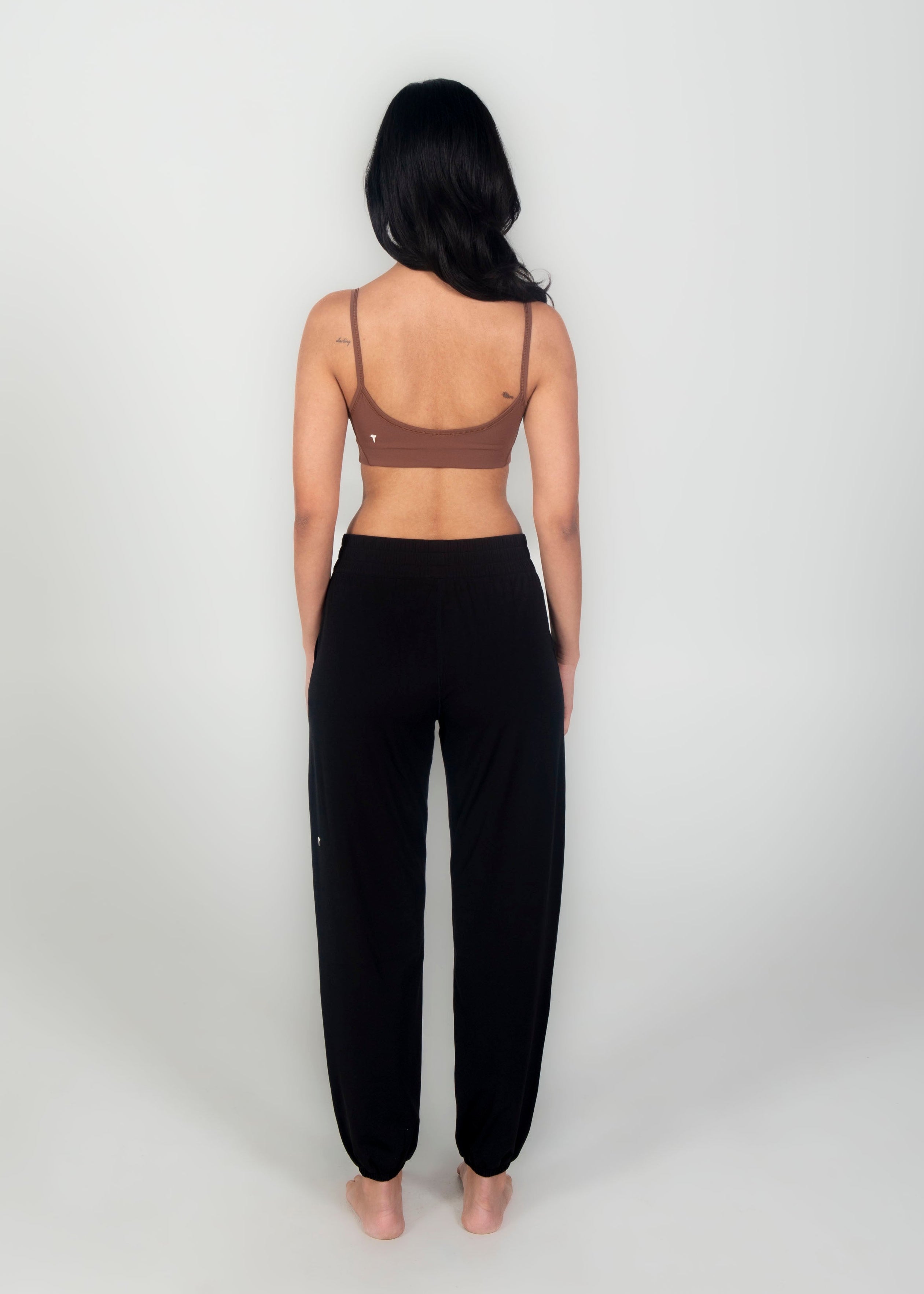 Woman wearing a black sports bra and black leggings on a white background