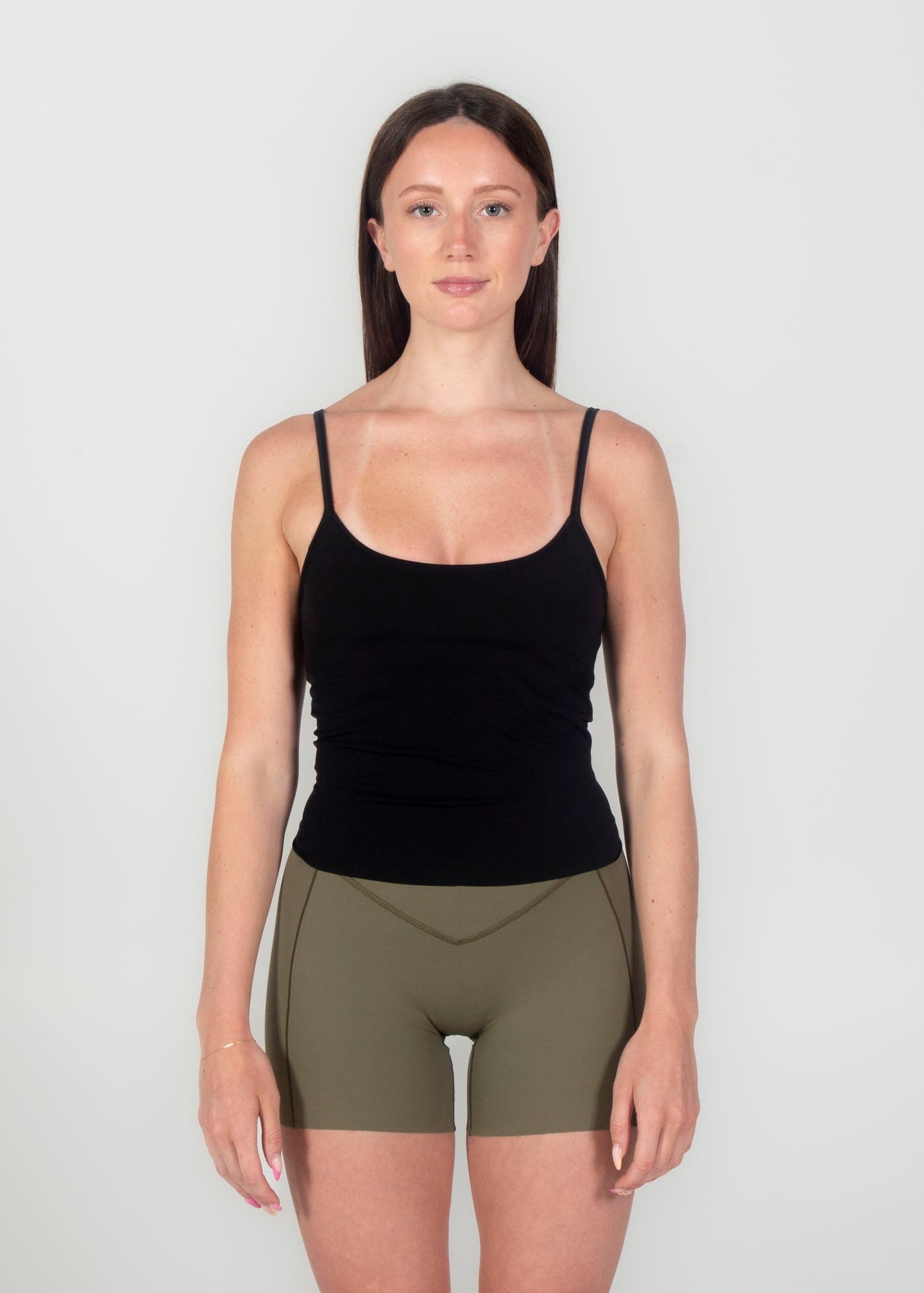 Woman wearing a black tank top and green shorts on a white background