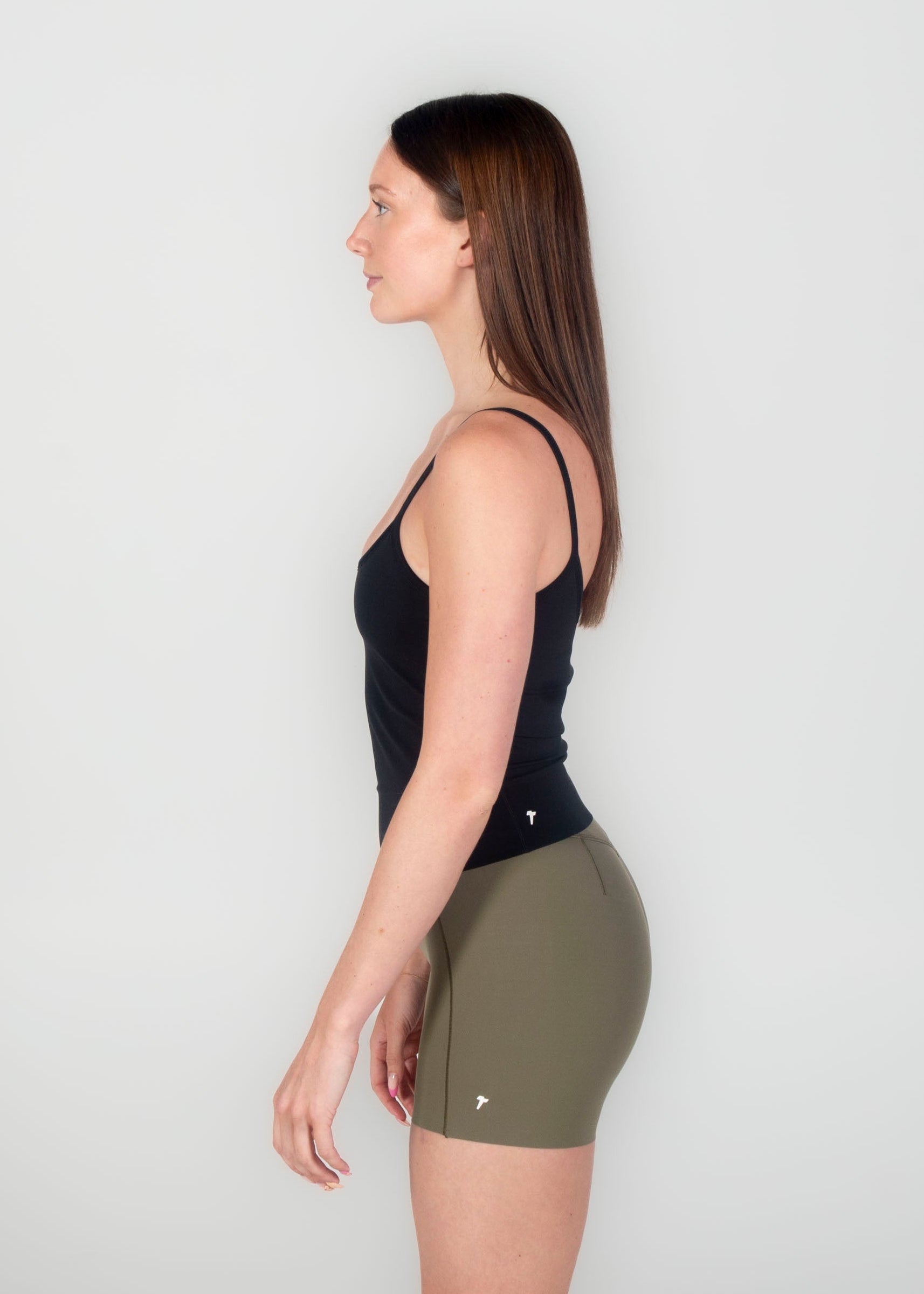 Woman wearing a black tank top and green shorts on a white background