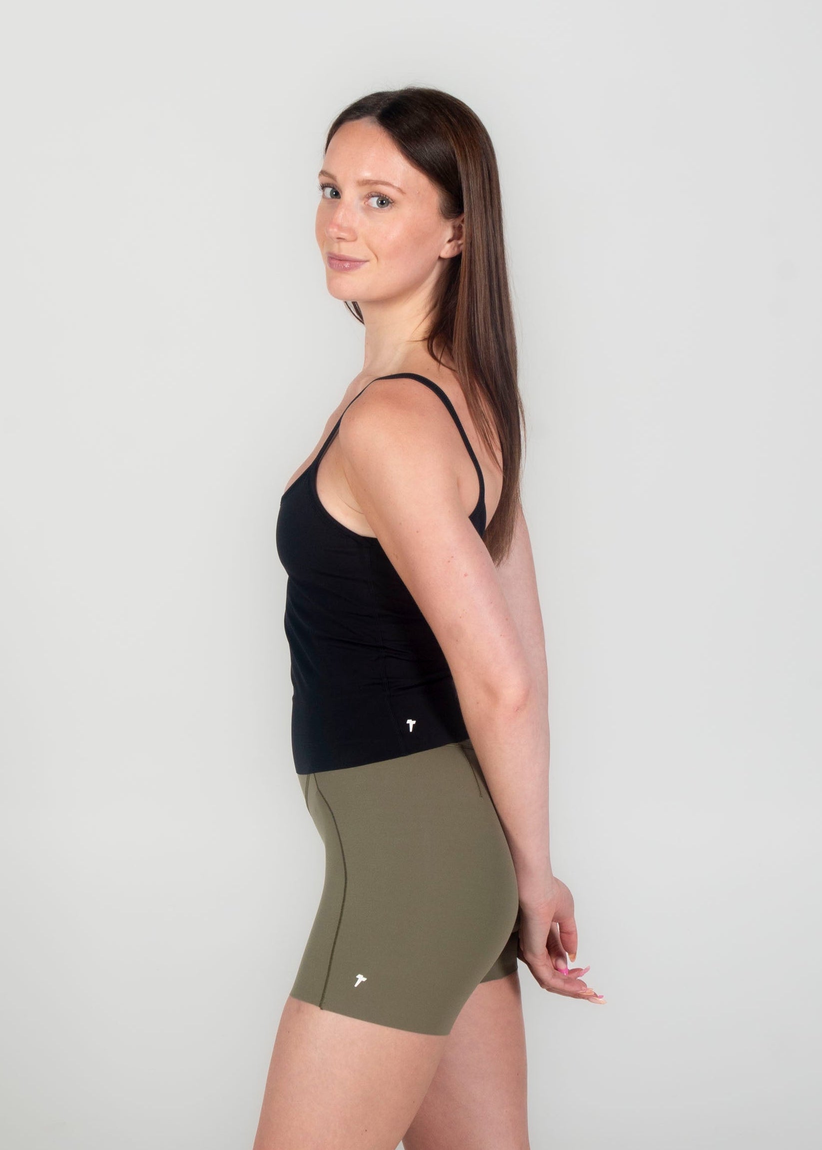 Woman wearing a black top and green shorts on a white background