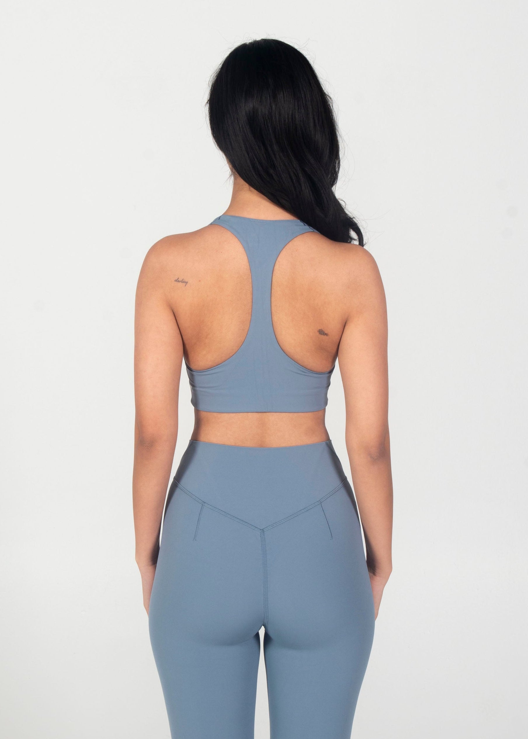 Person wearing a gray sports bra and leggings set on a white background