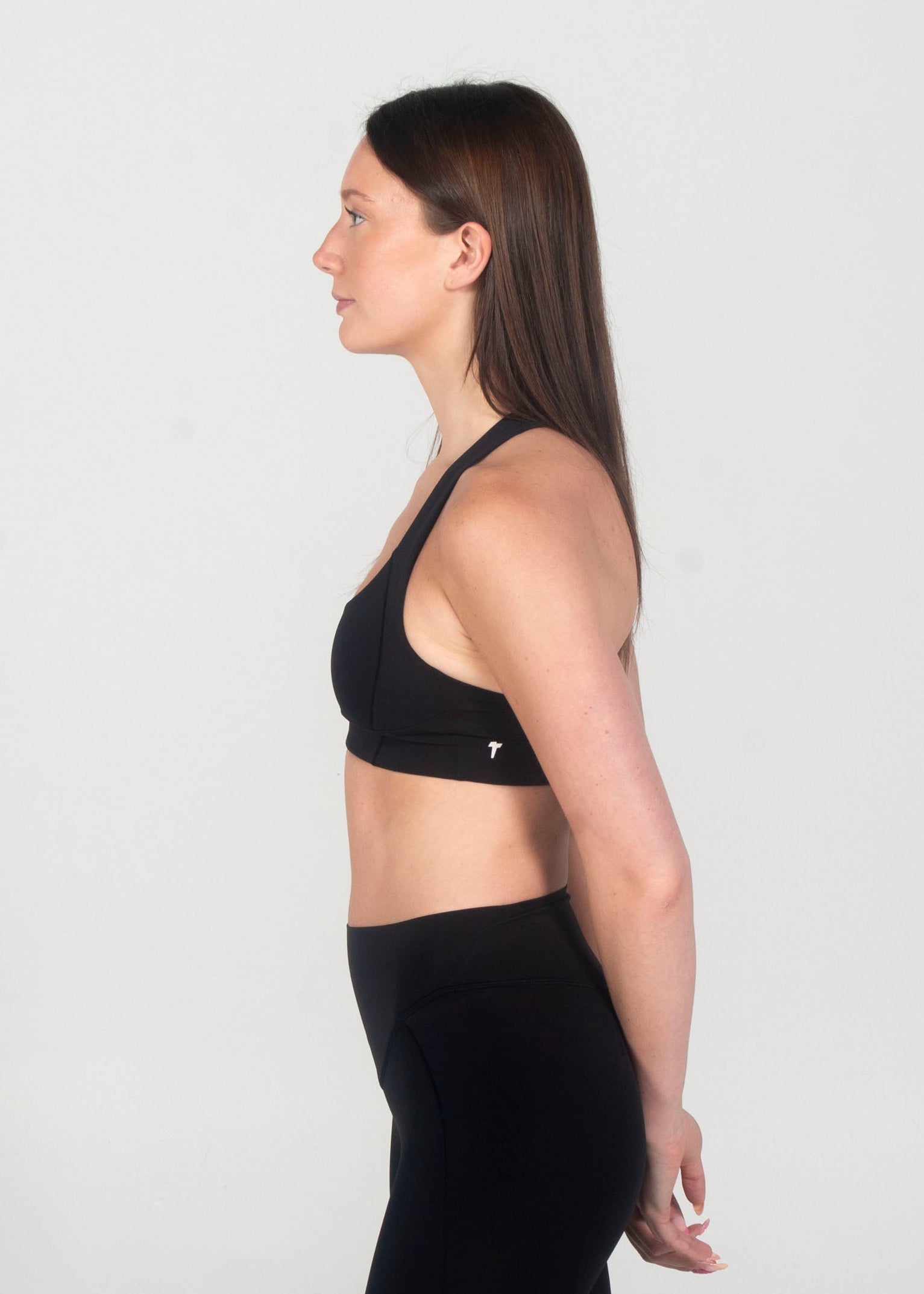 Woman wearing a black sports bra and black leggings on a white background