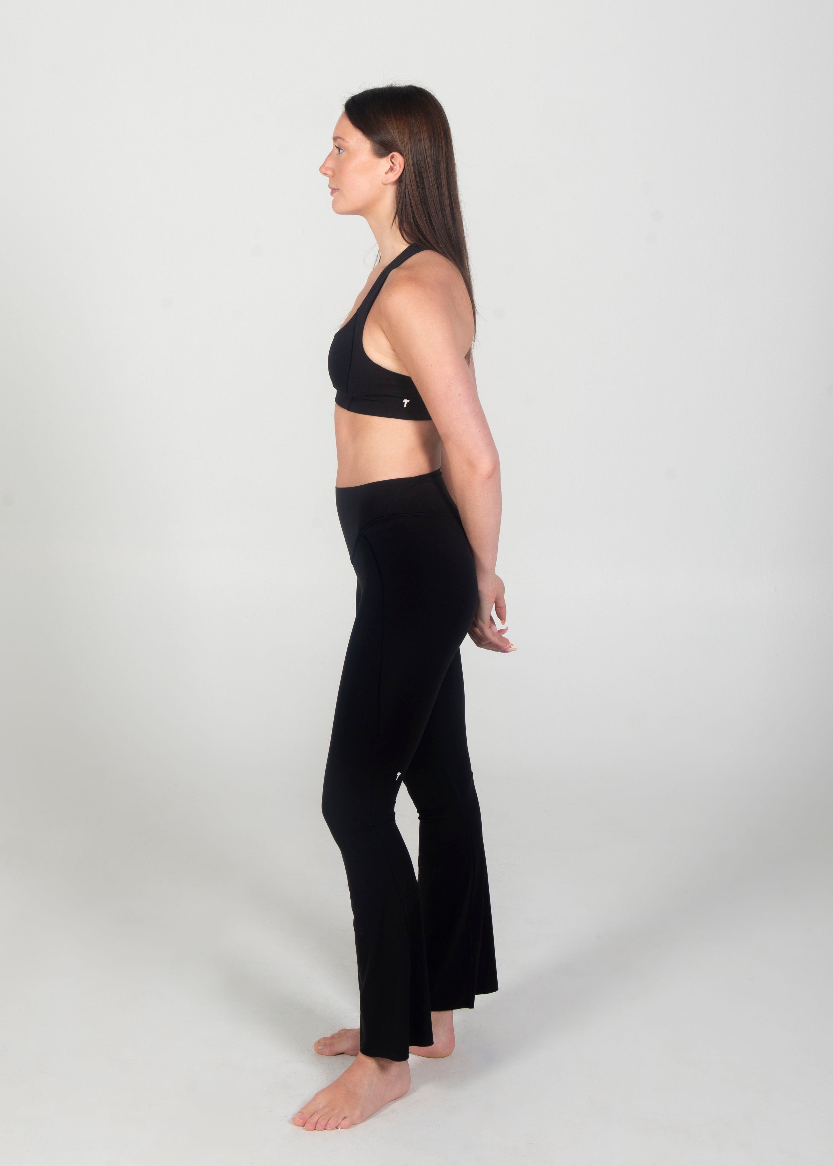 Woman wearing a black sports bra and black leggings on a white background