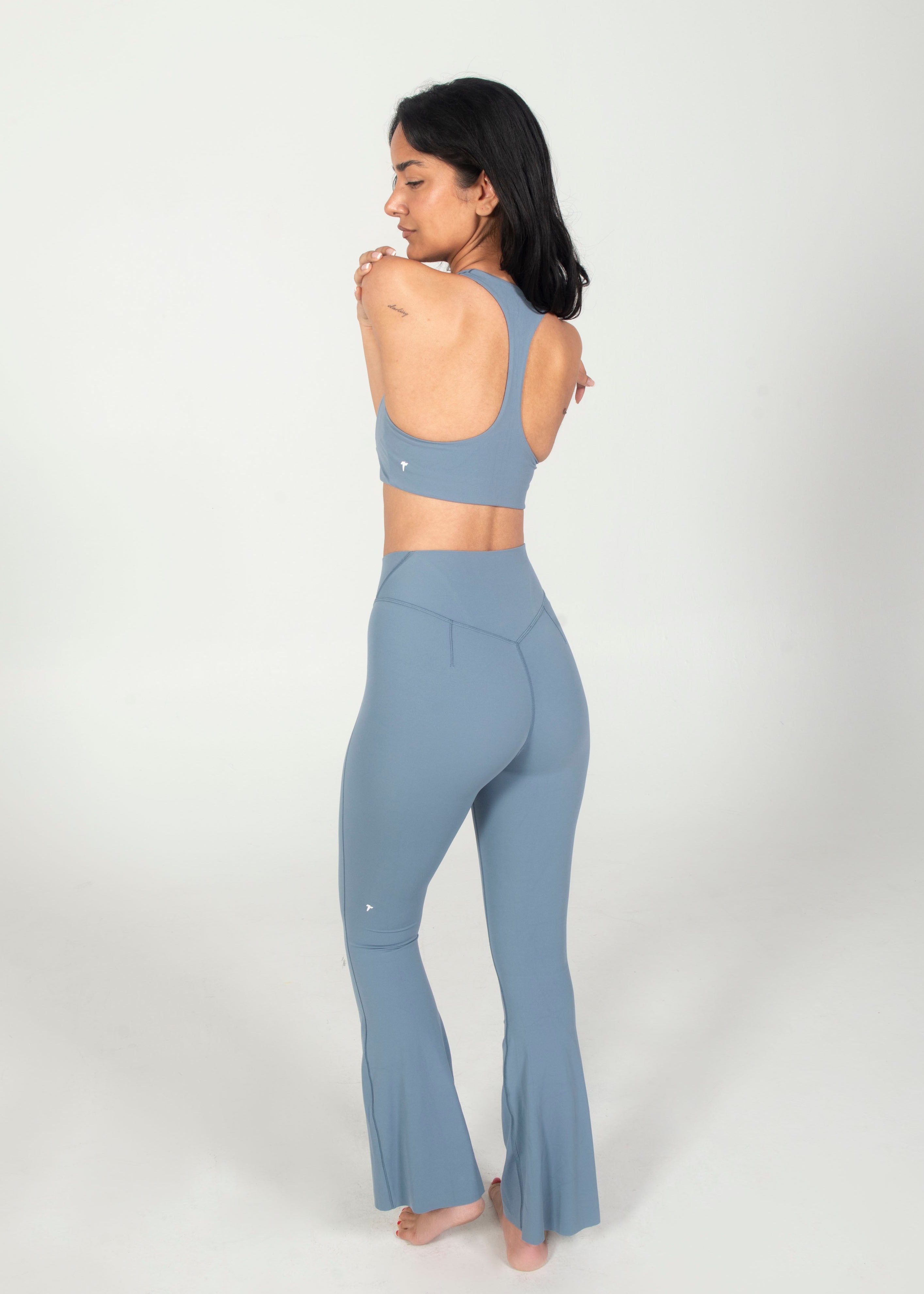 Woman wearing a matching blue sports bra and leggings set on a white background