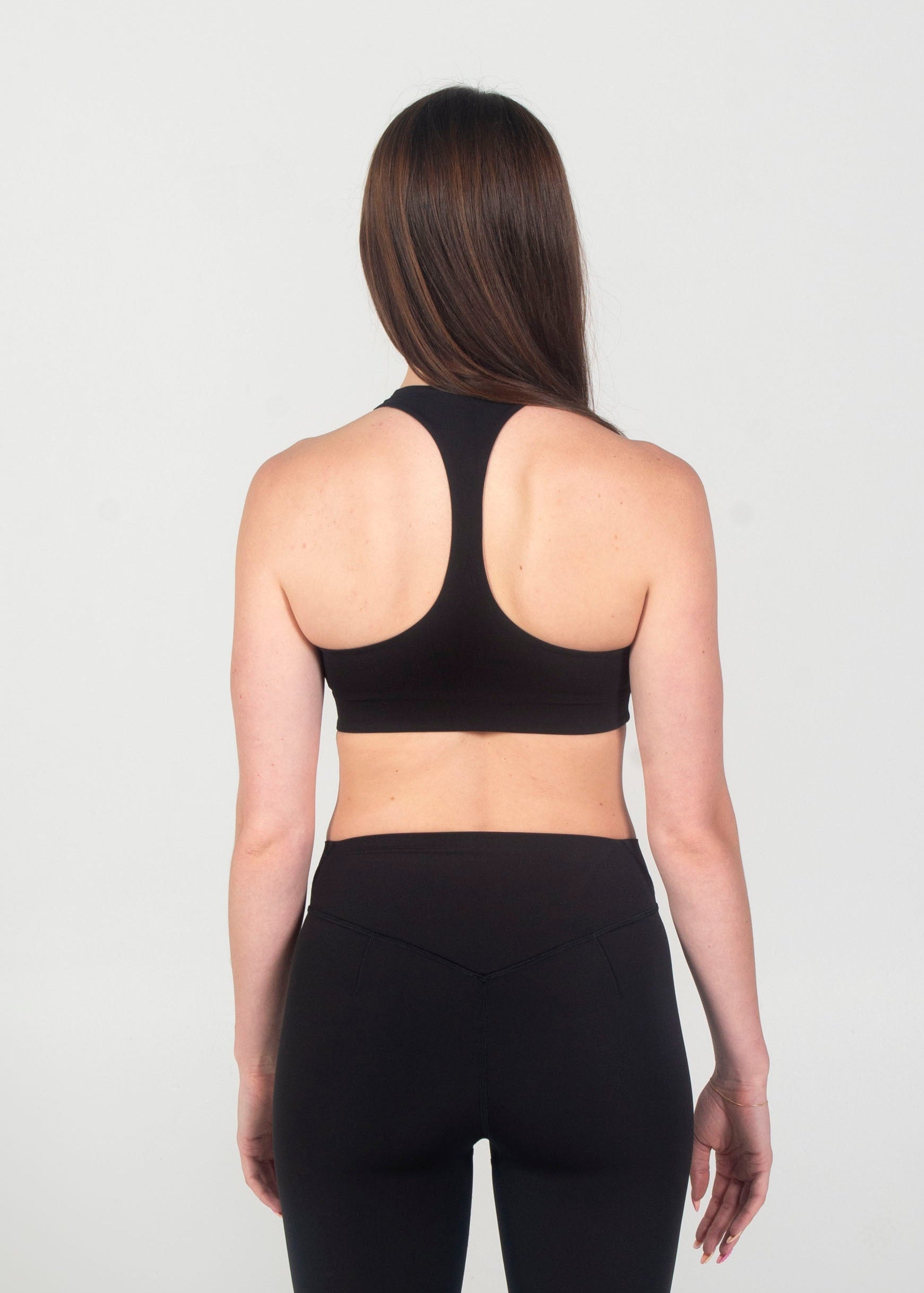 Person wearing a black sports bra and leggings on a white background