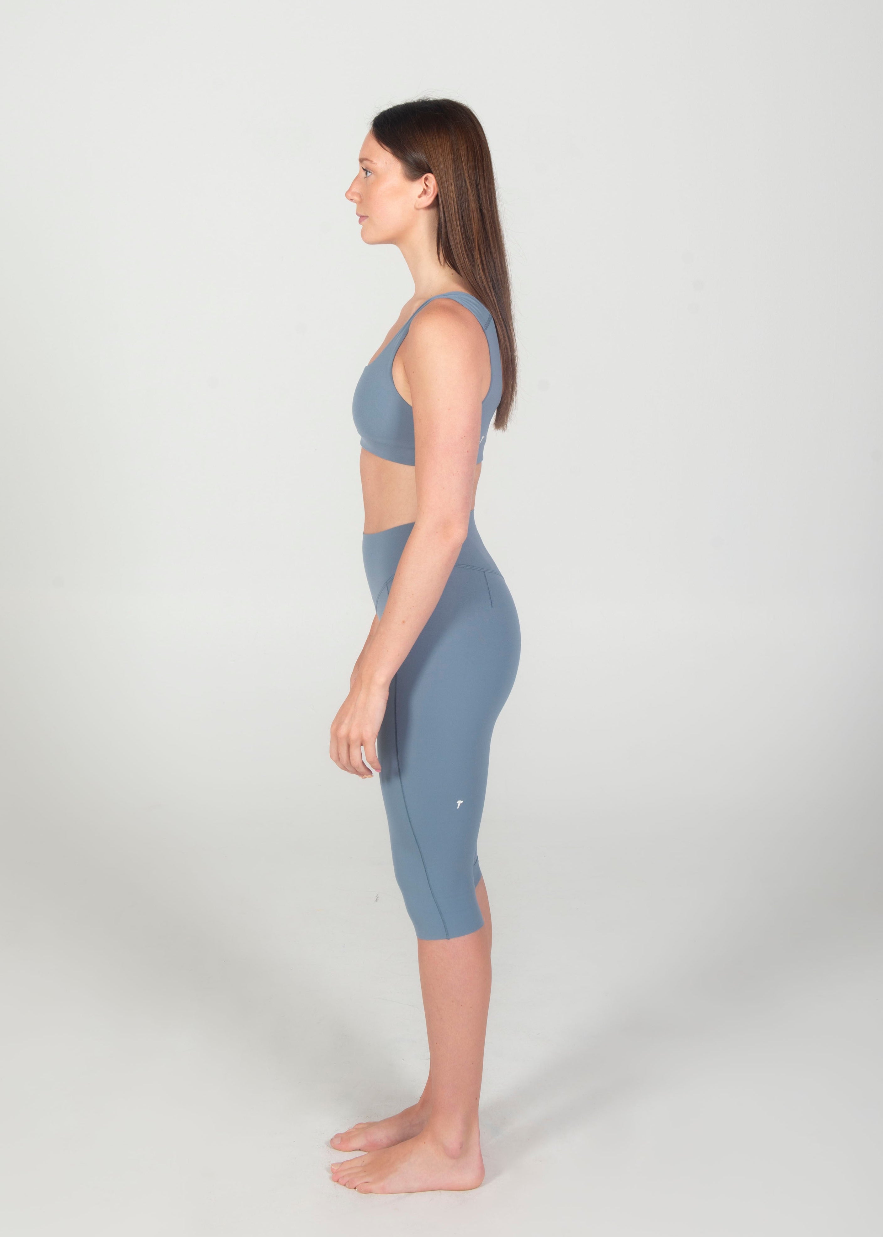 Woman wearing a blue athletic outfit standing against a white background