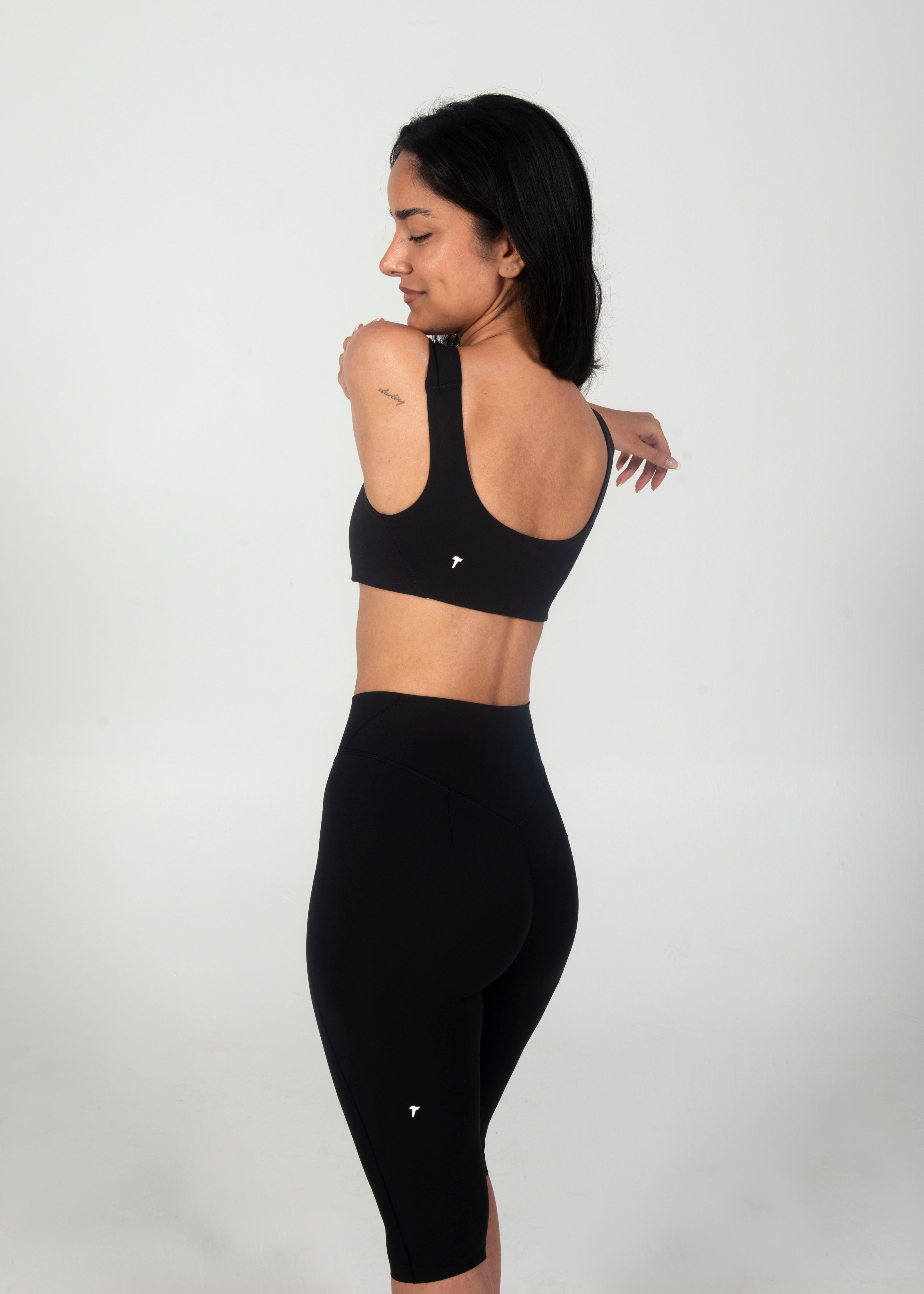 Woman wearing a black sports bra and leggings on a white background