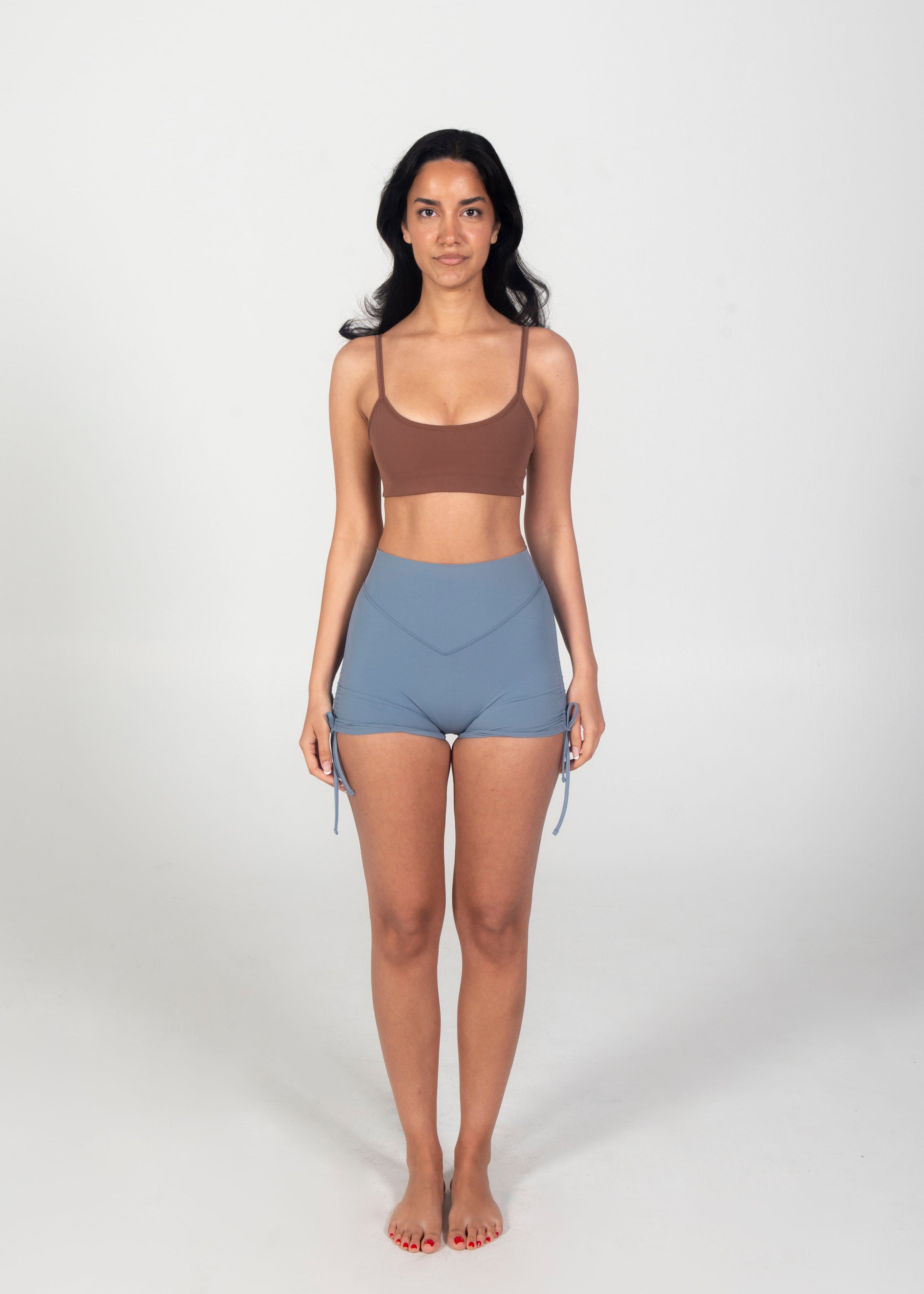 Woman wearing a brown tank top and blue shorts on a white background