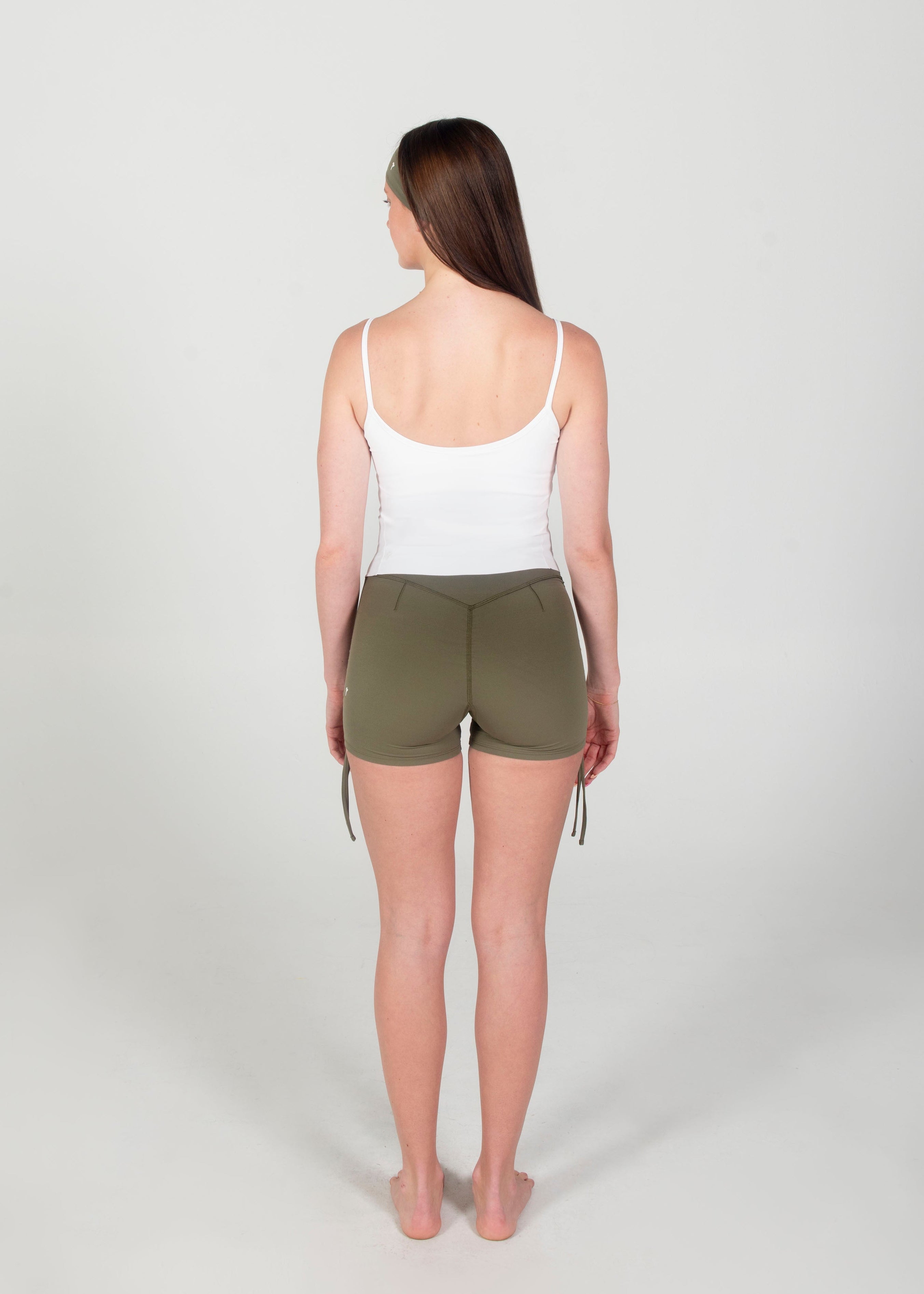 Woman wearing a white tank top and green shorts on a white background
