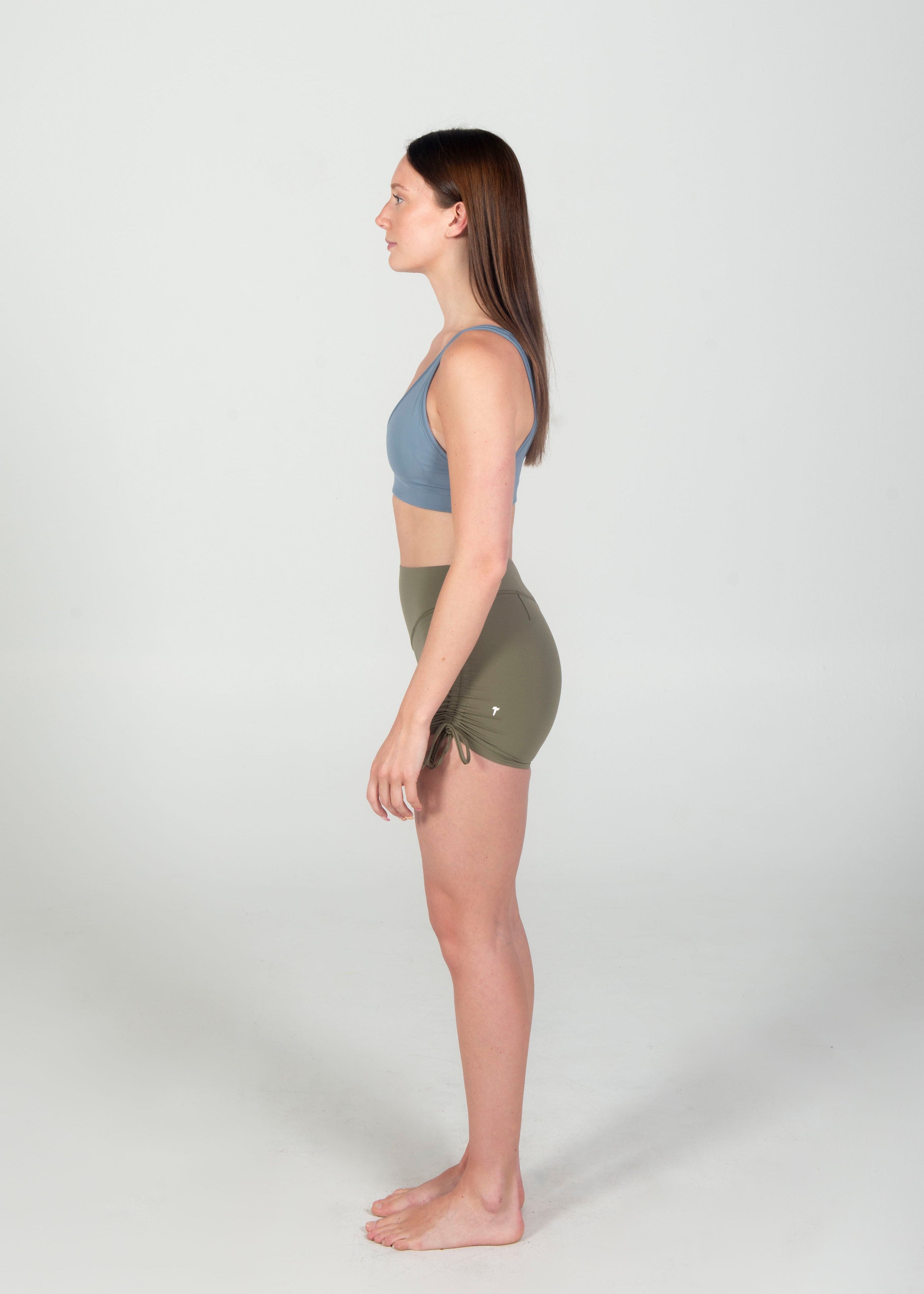 Woman wearing a sports bra and shorts on a white background