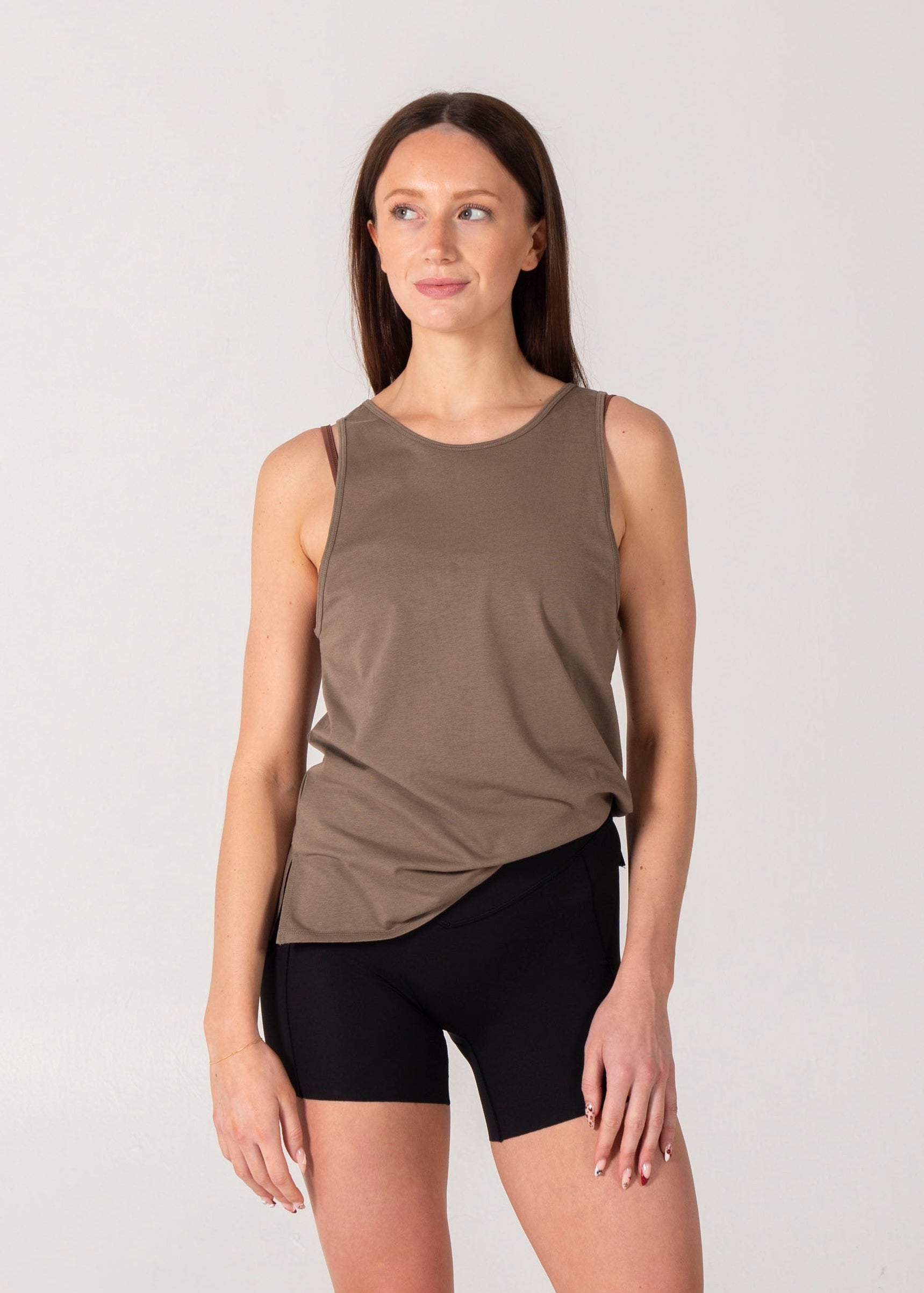 Woman wearing a brown tank top and black shorts on a white background