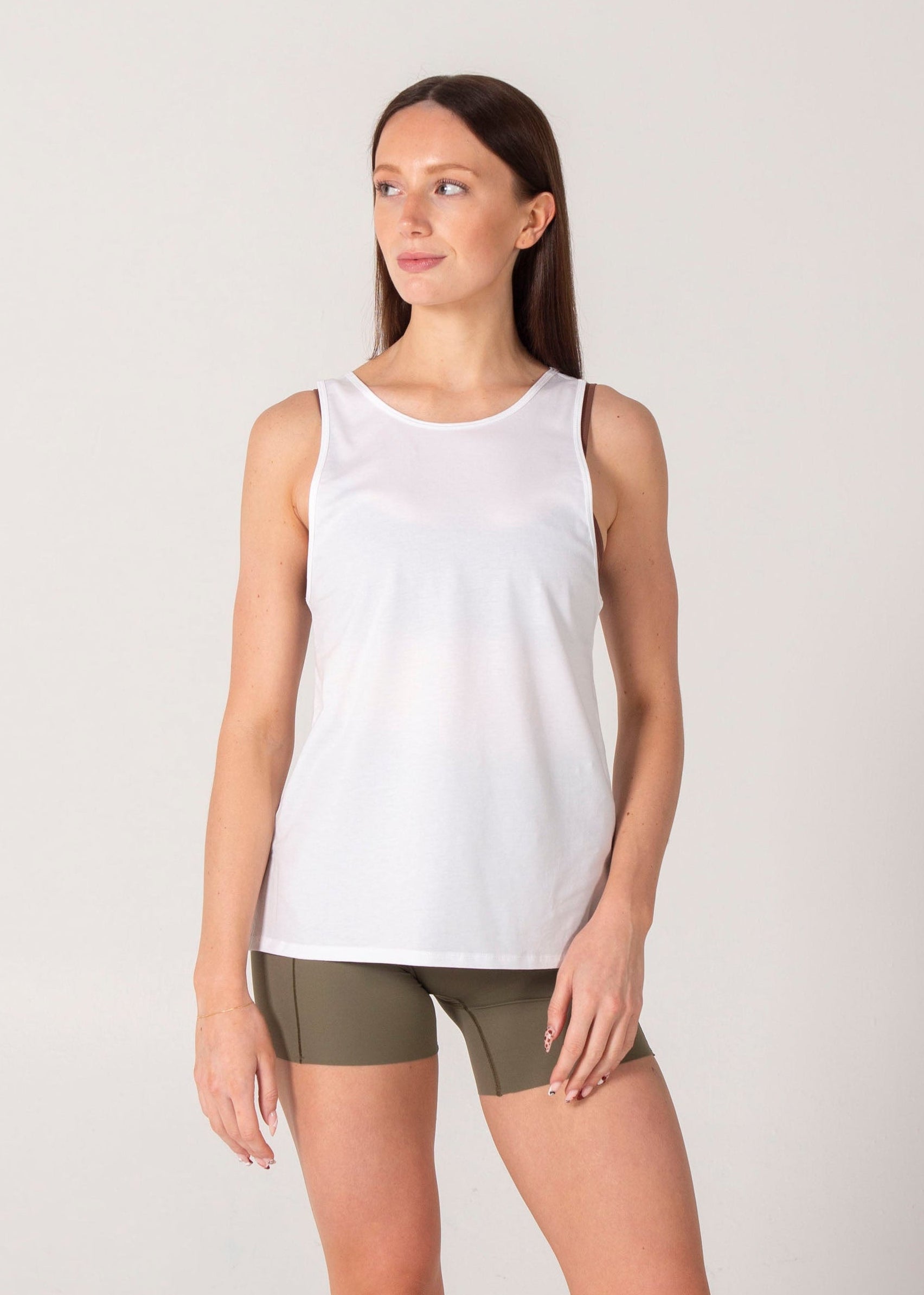 Woman wearing a white tank top and green shorts on a plain background