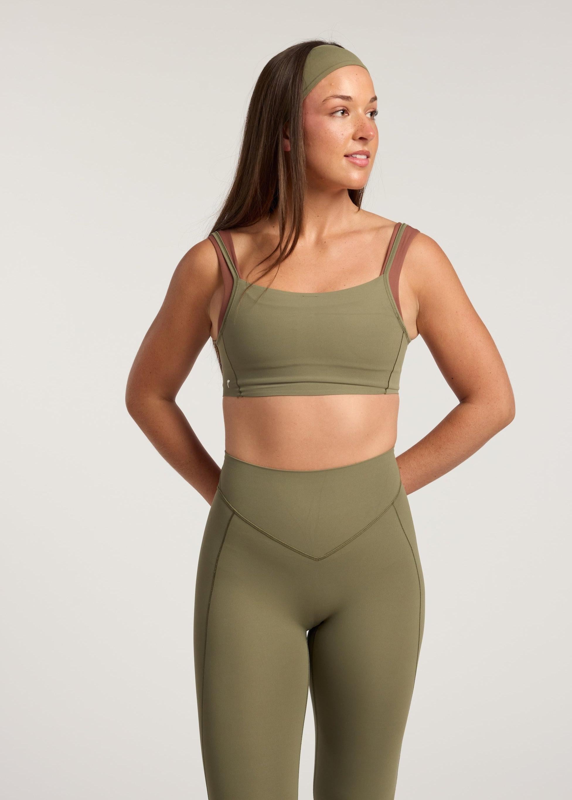 Woman wearing a green sports bra and leggings set on a light gray background