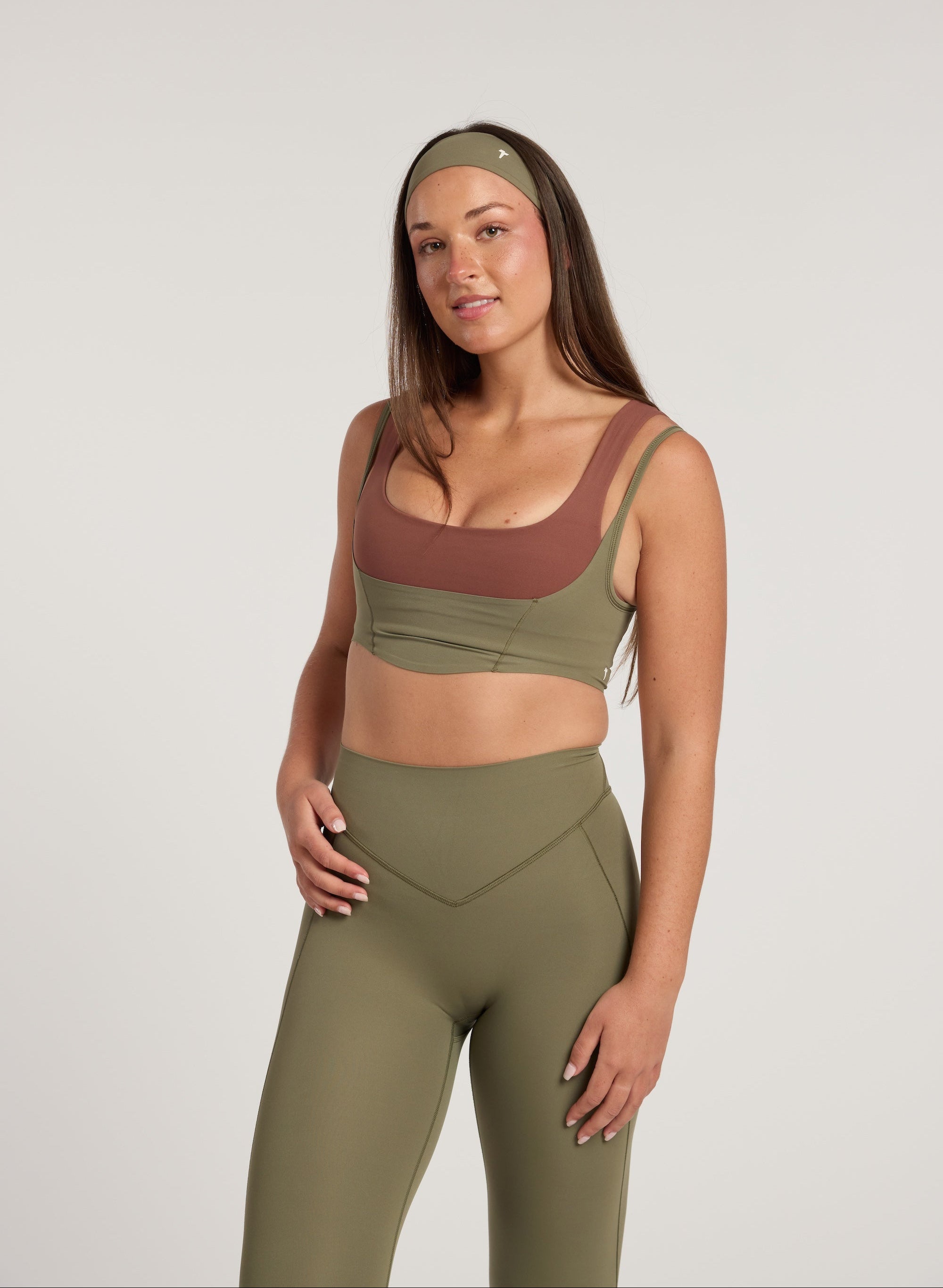 Woman wearing a green sports bra and leggings set on a plain background