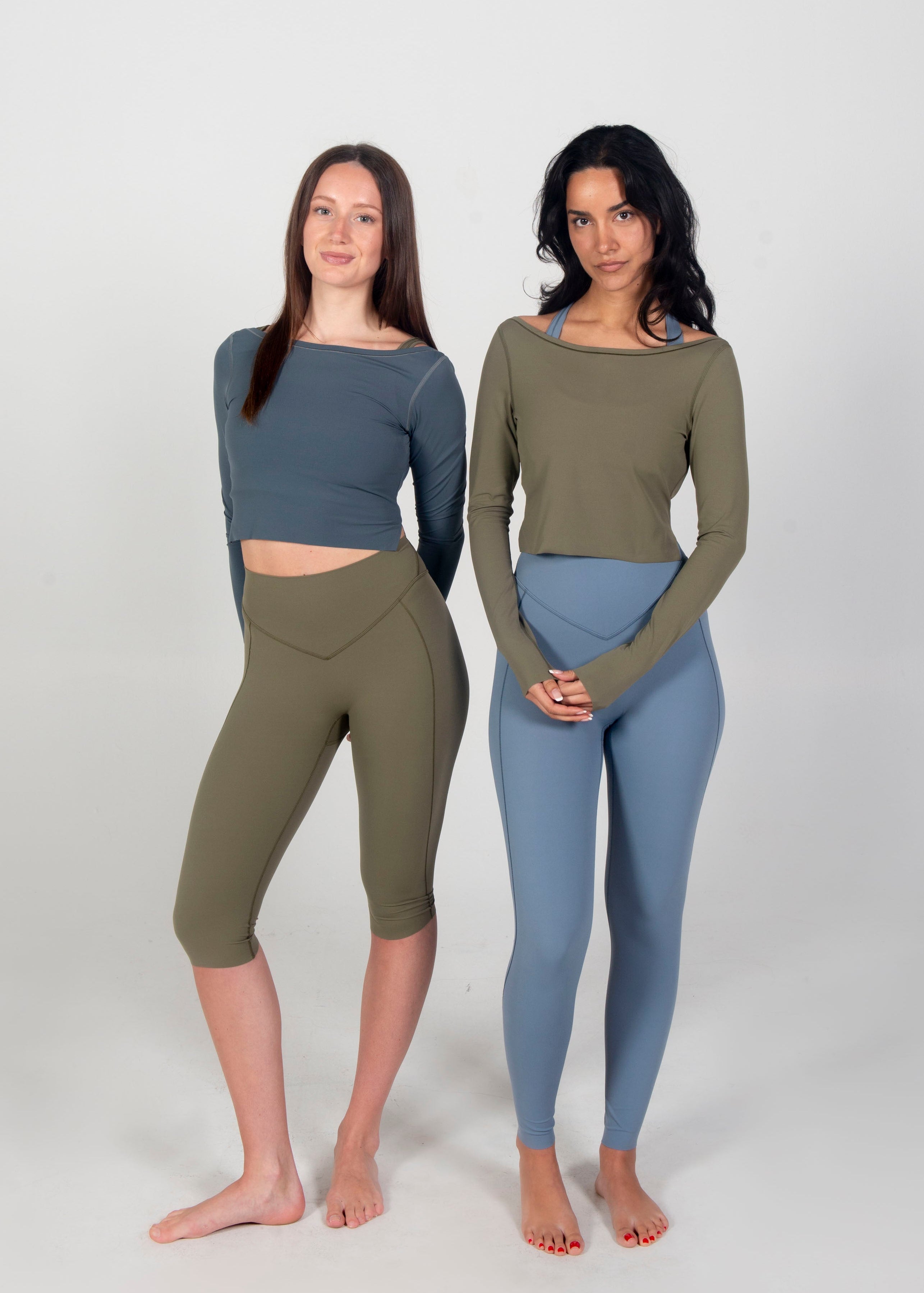 Two women wearing matching outfits of long-sleeve tops and leggings on a white background