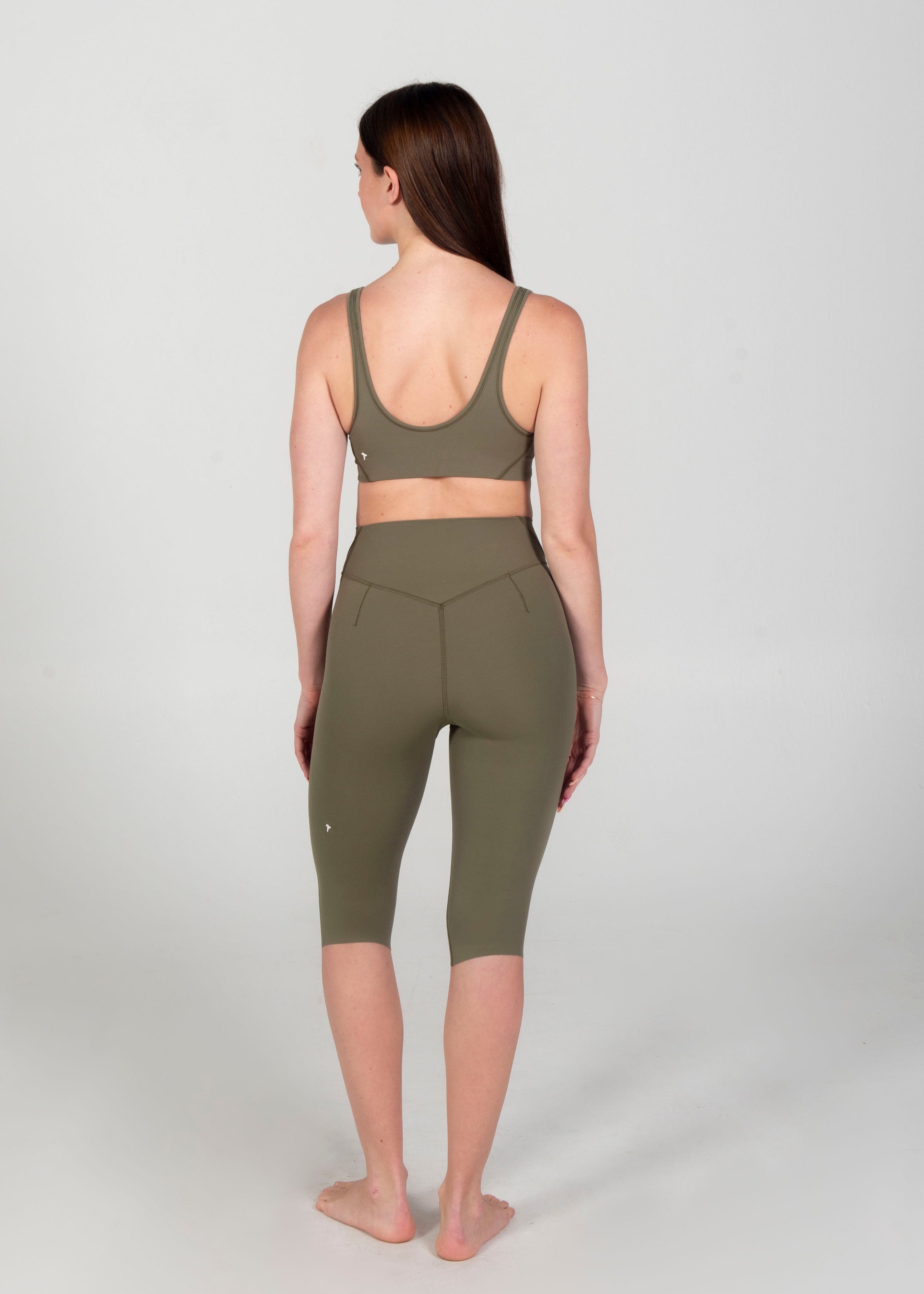 Person wearing green athletic leggings and sports bra on a white background