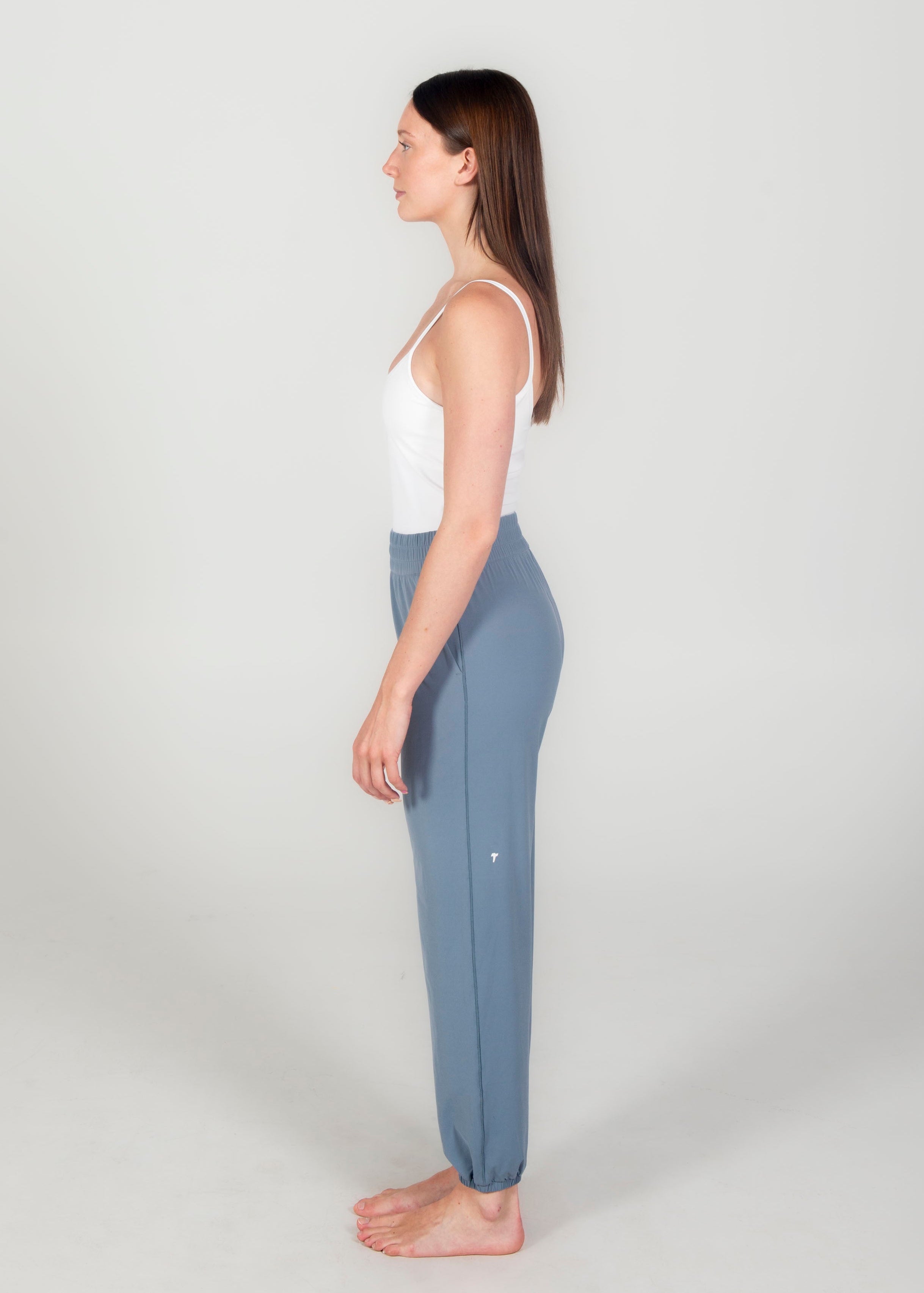 Woman wearing a white top and blue yoga pants on a light gray background