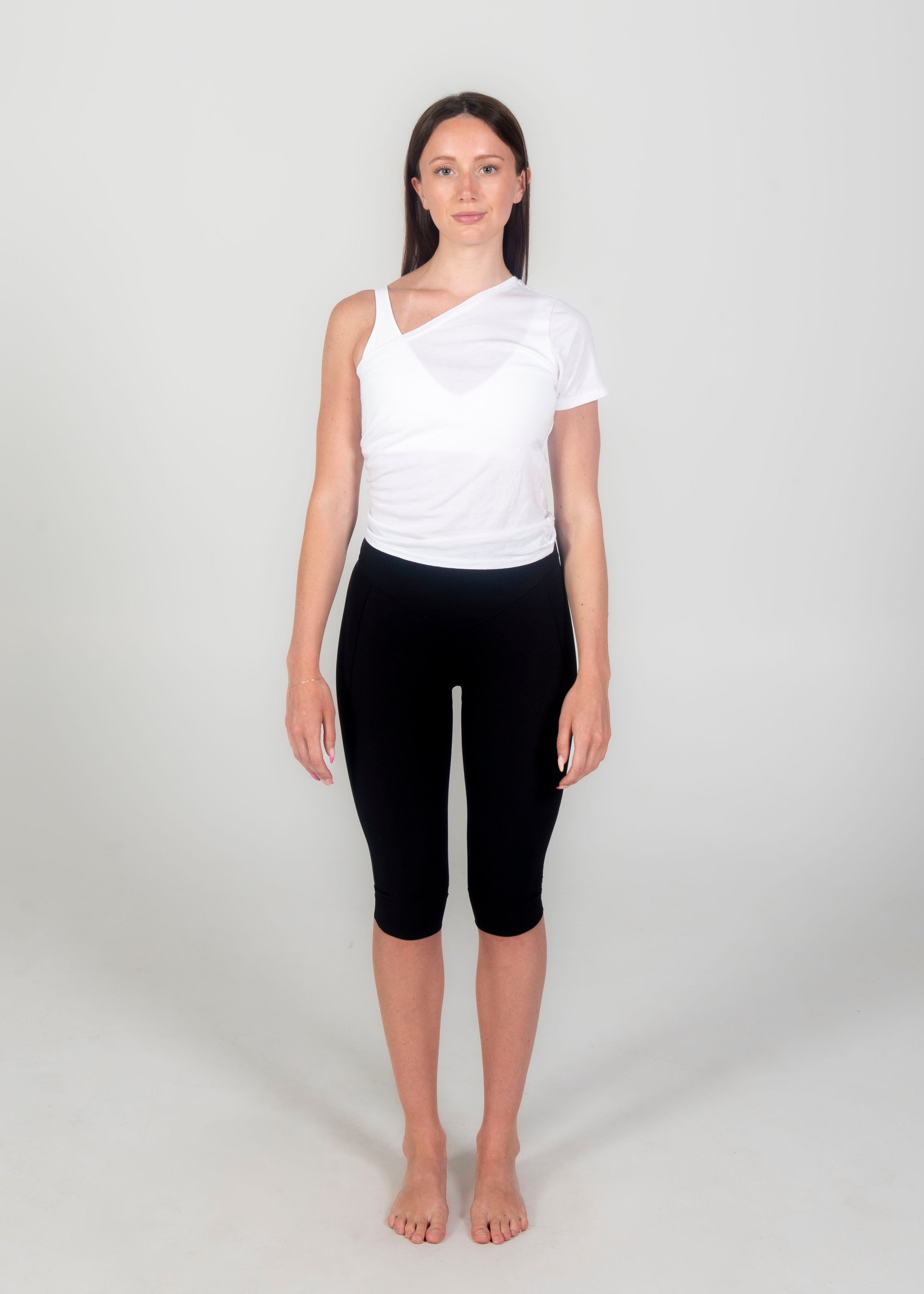 Woman wearing a white sleeveless top and black capri pants on a white background