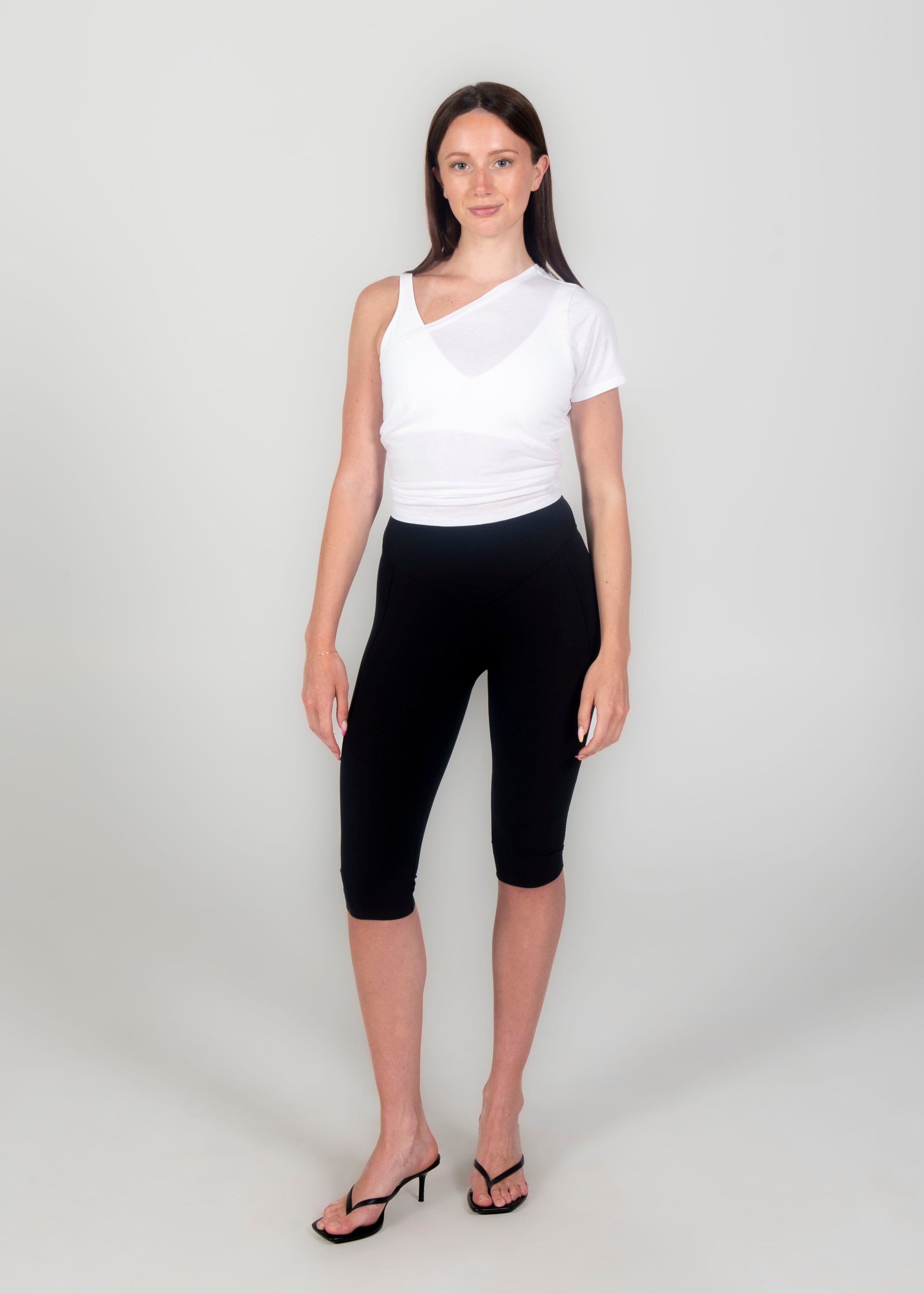 Woman wearing a white top and black capri pants on a white background