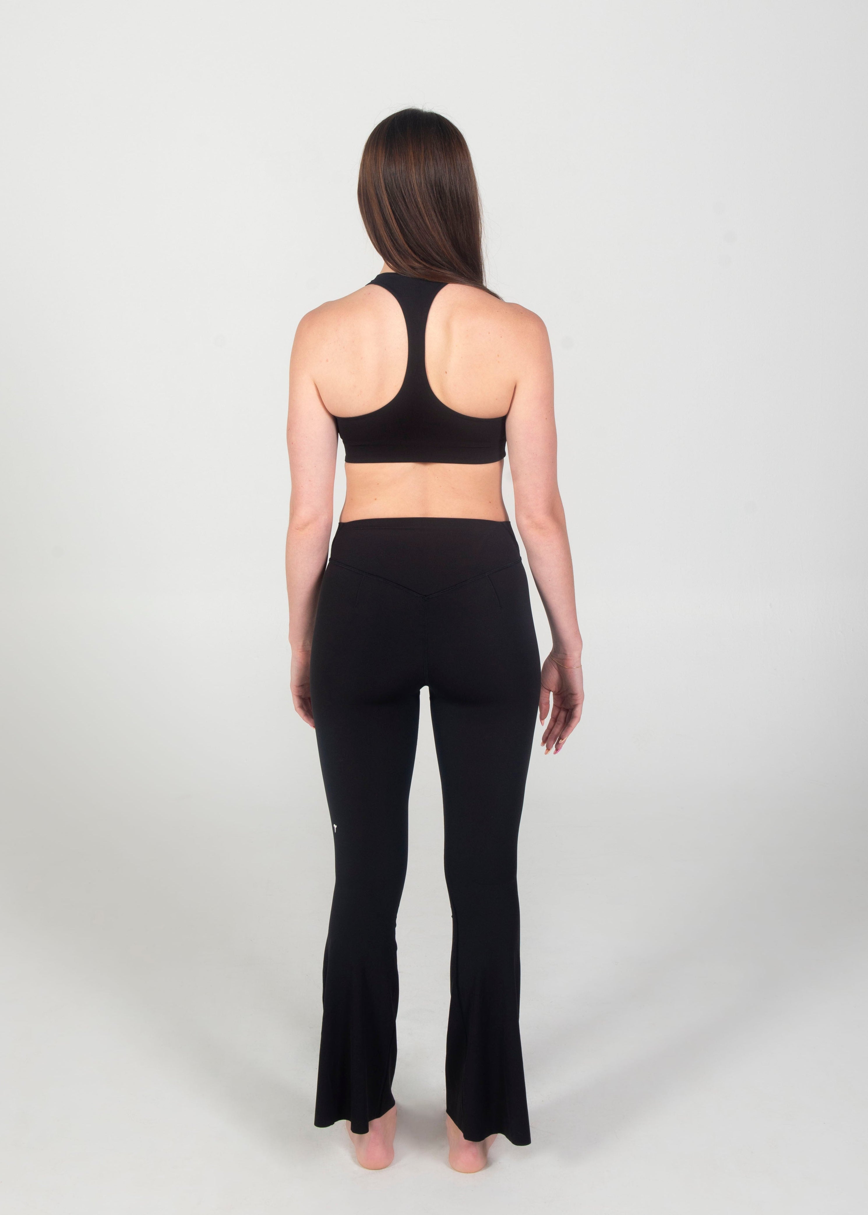 Person wearing a black sports bra and leggings on a white background