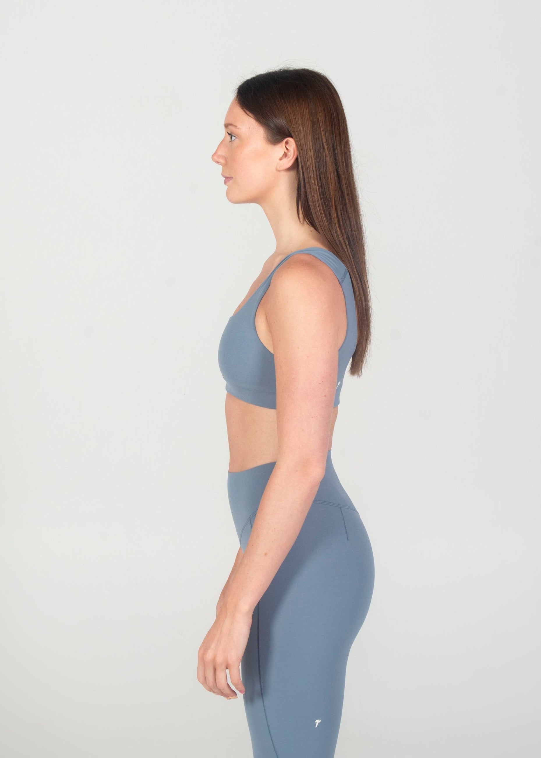 Woman wearing a blue athletic outfit standing against a white background