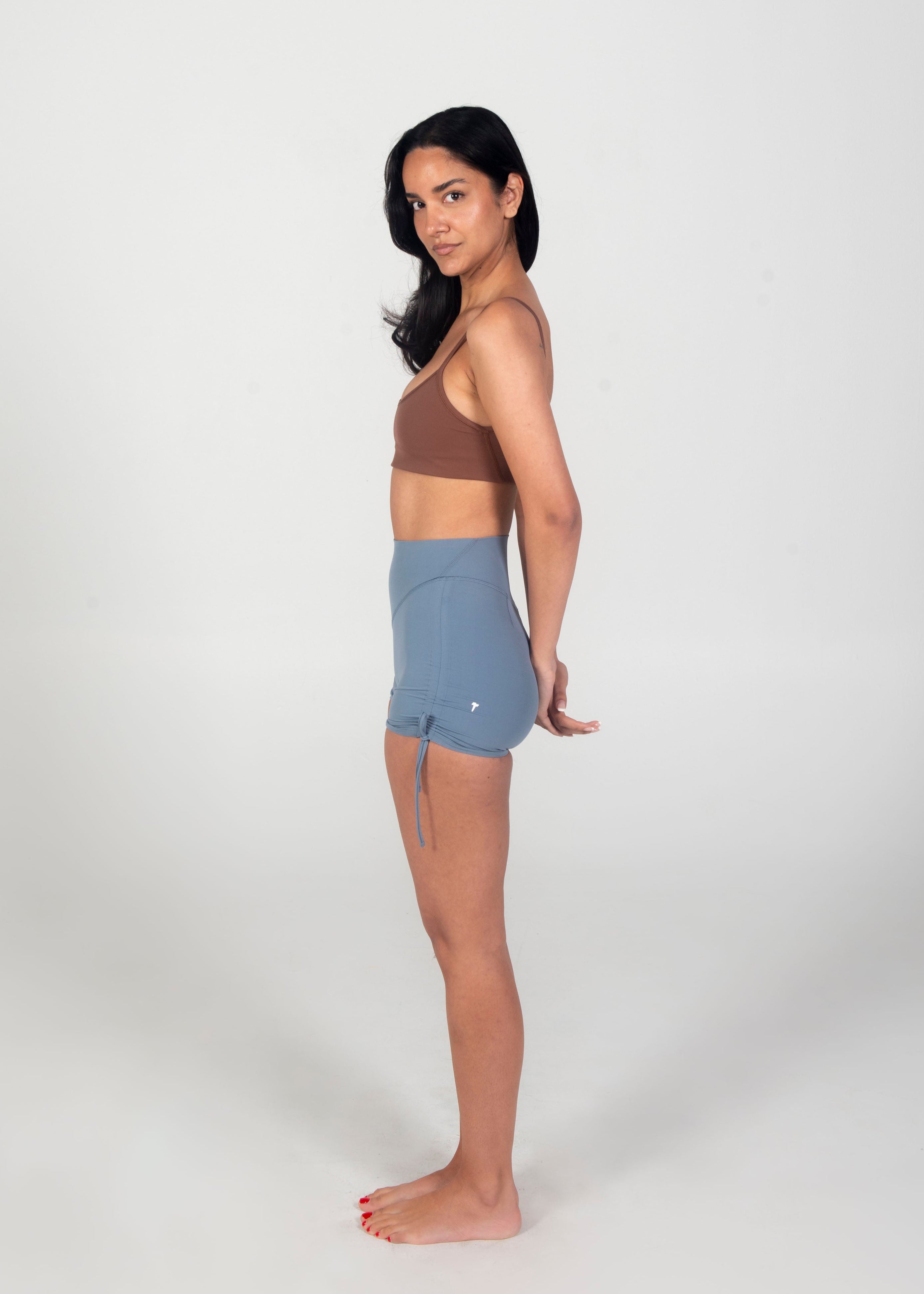 Woman wearing a brown top and blue shorts on a white background