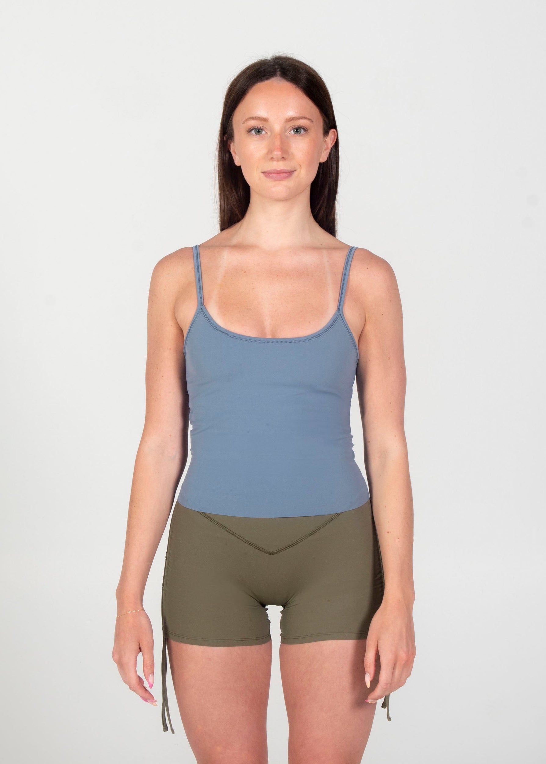 Woman wearing a blue tank top and green shorts on a white background