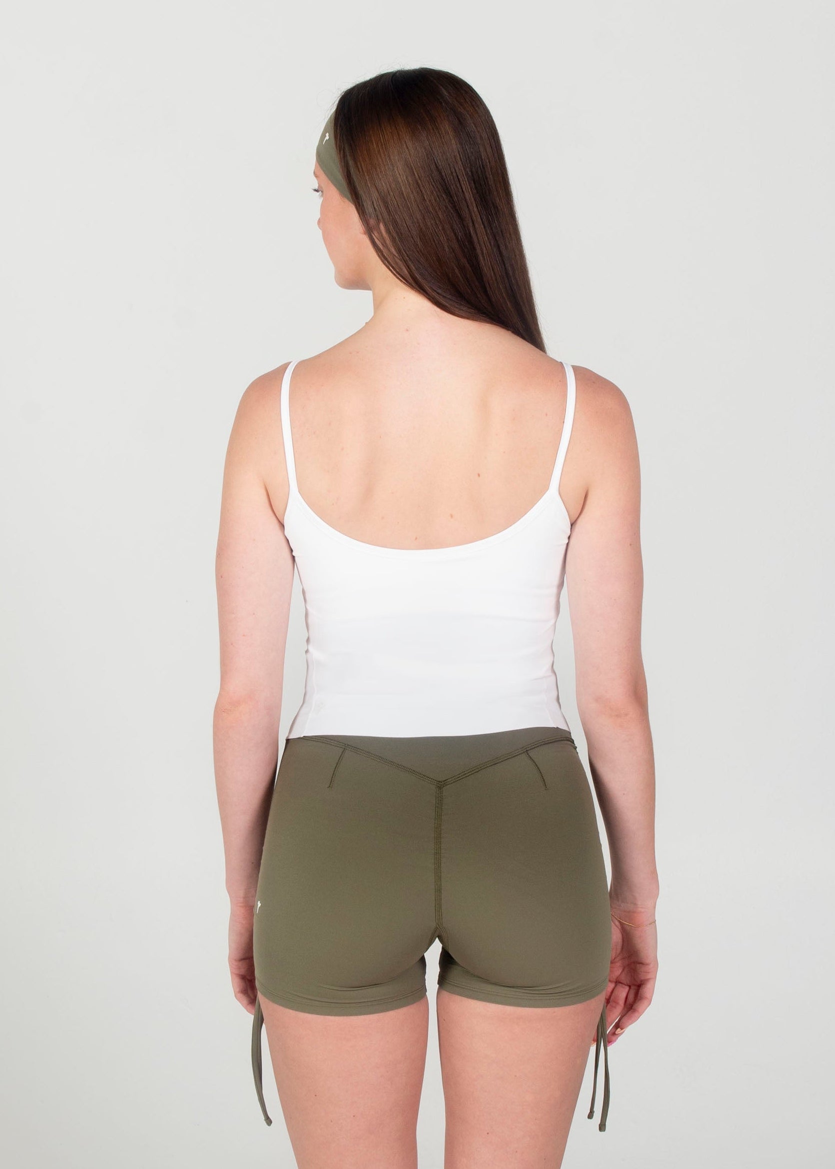 Woman wearing a white tank top and green shorts on a white background