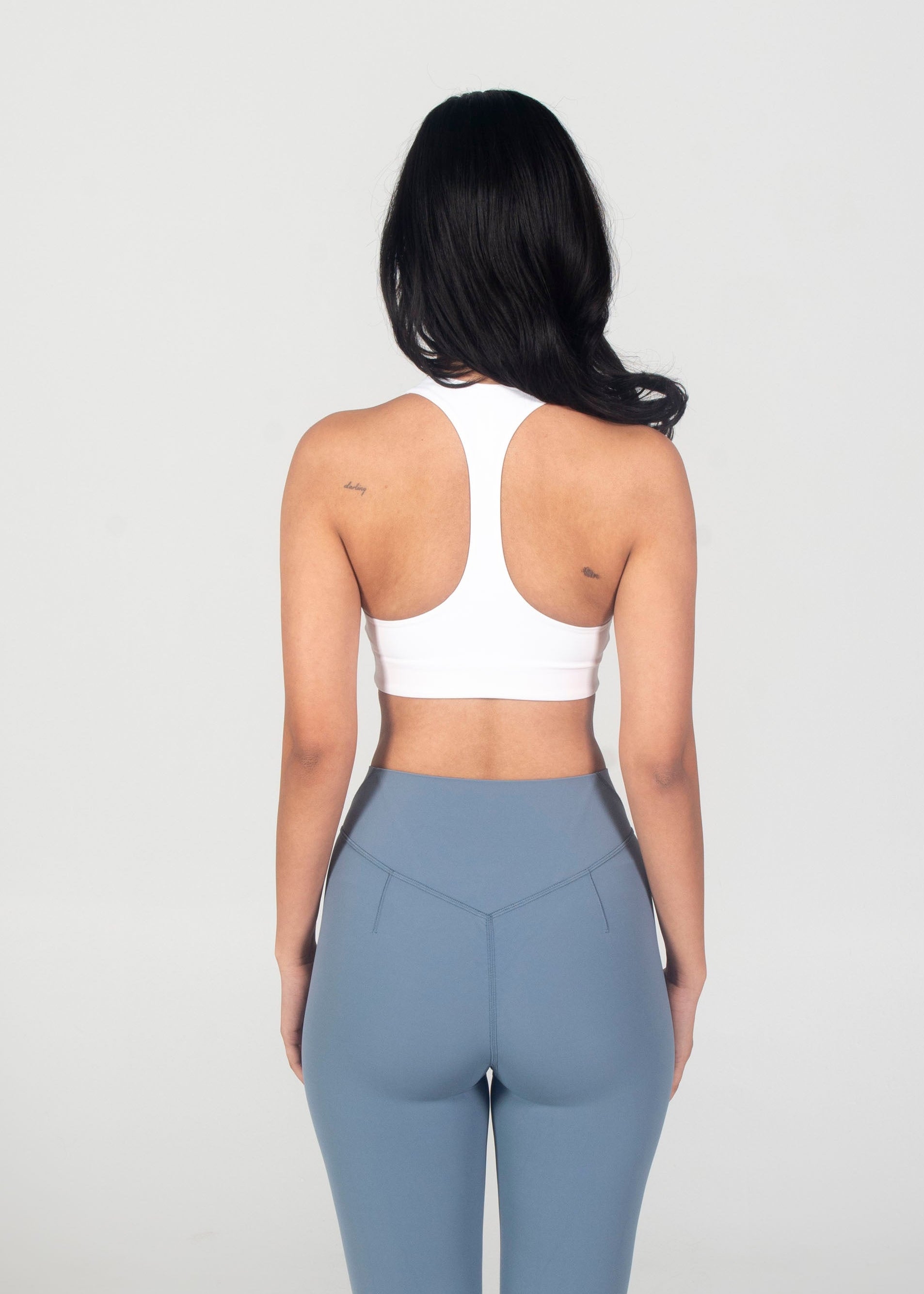 Person wearing a white top and light blue flared pants on a white background