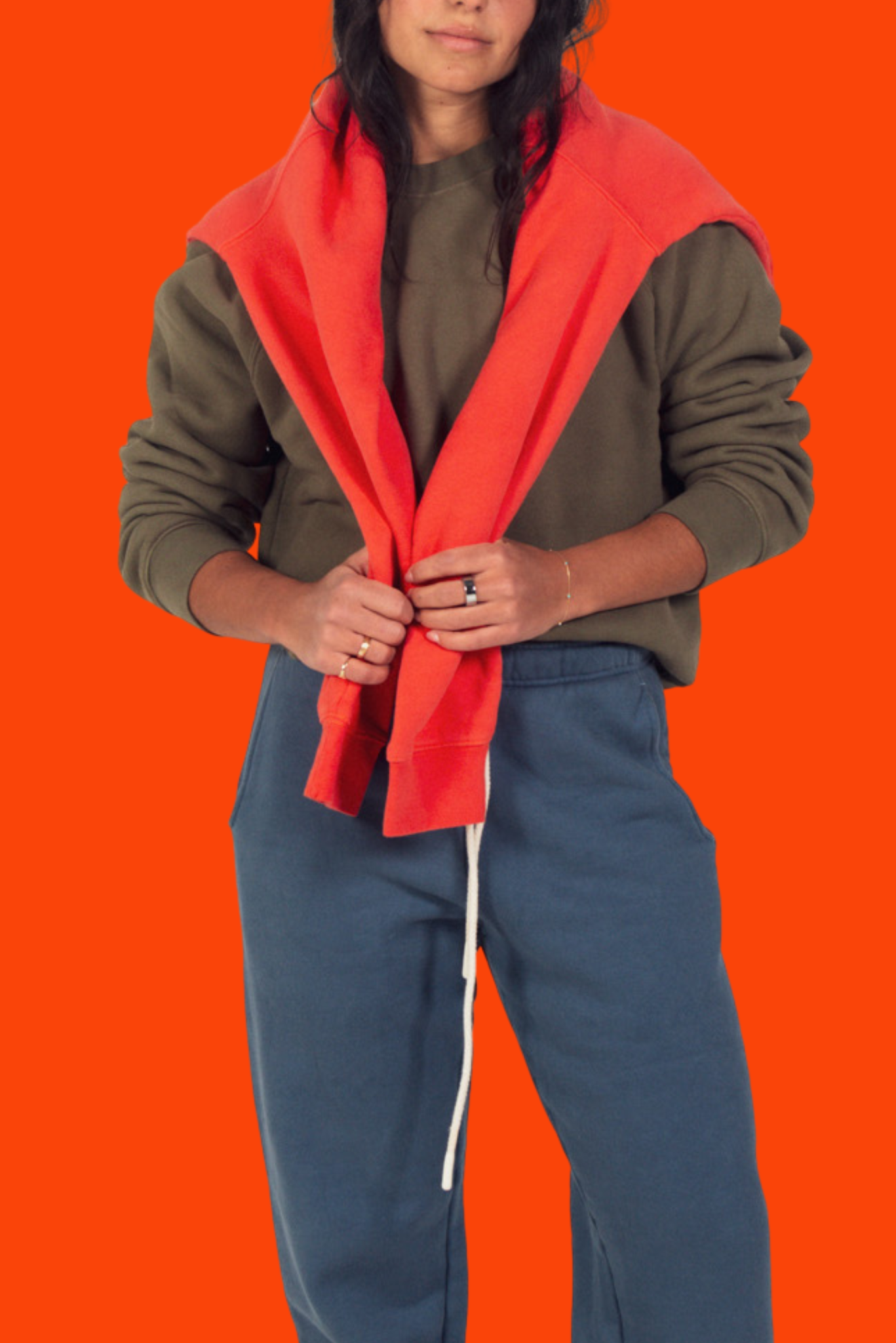 Person wearing a red jacket over a green sweater on an orange background
